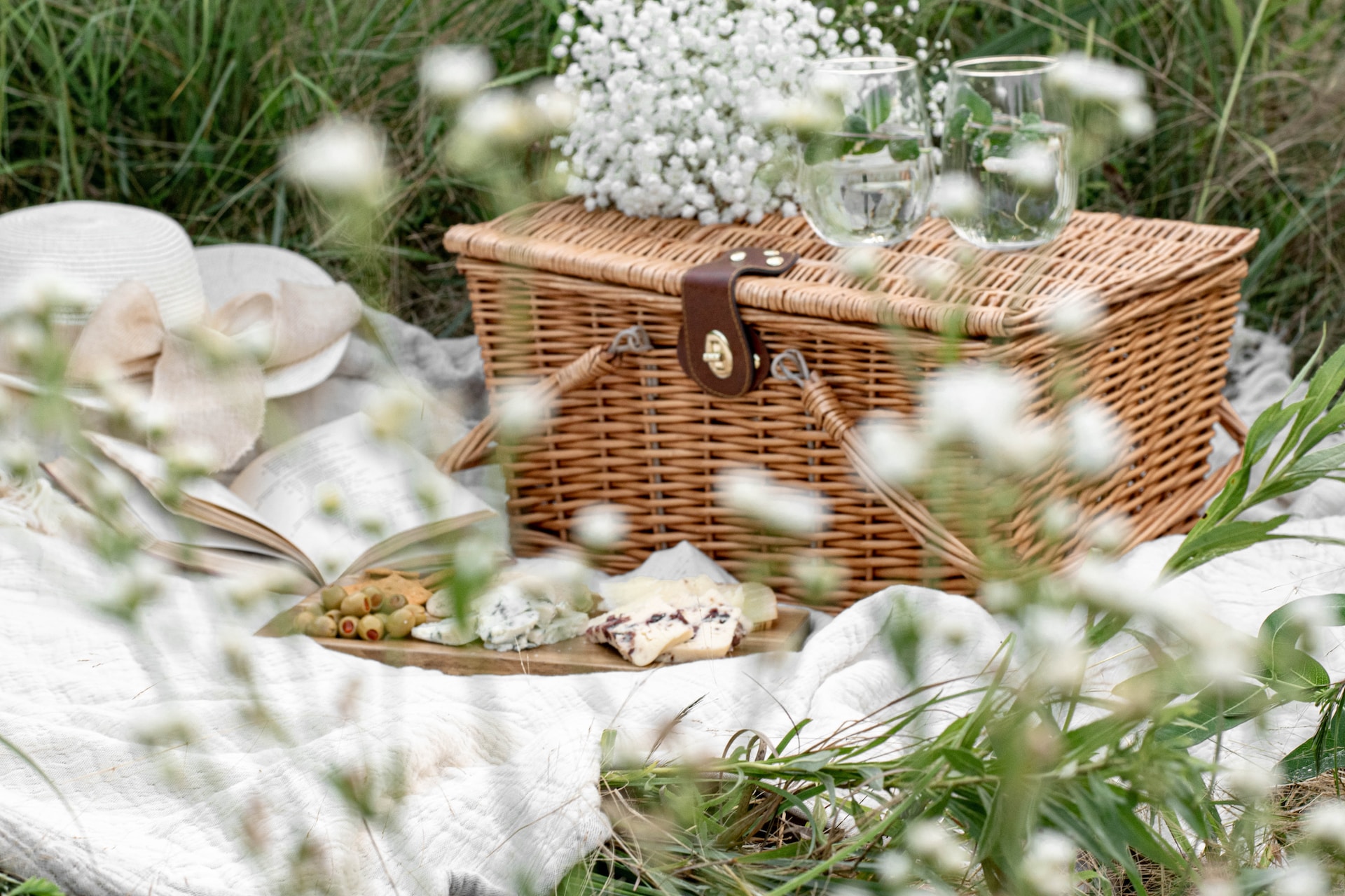 A picnic basket and glasses of wine a brown picnic basket